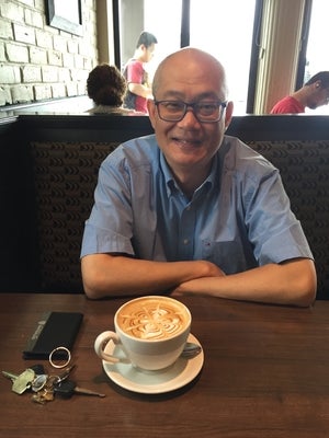 Wayne Chang at a table with a coffee and a smile