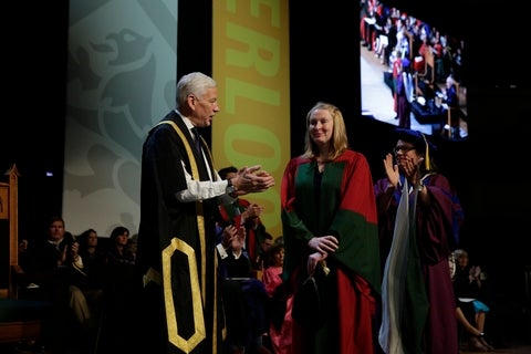 Dominic Barton congratulating PhD student while being hooded. 