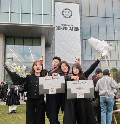 Four graduates posing with their degree