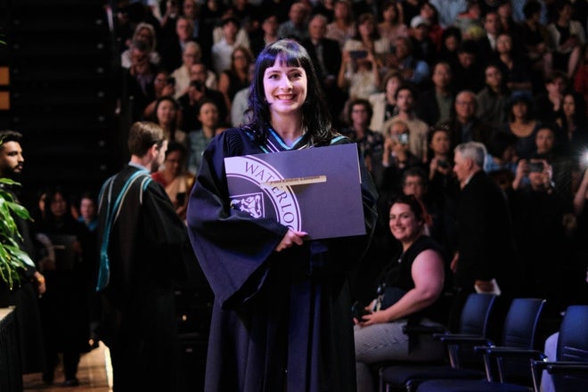 Graduate posing with degree after crossing the stage