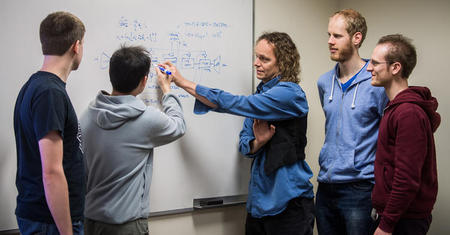 Chris Eliasmith and students looking at an equation.