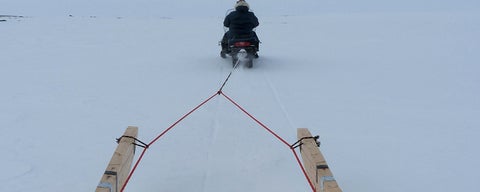 Inuit travelling by snow machine pulling qamutiik