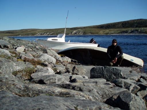 Bryan Grimwood stands in front of canoe on rocky shore of Thelon River.