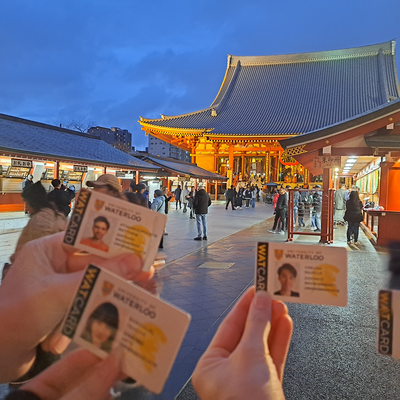 Students hold their watcards up in front of Japanese temple. 