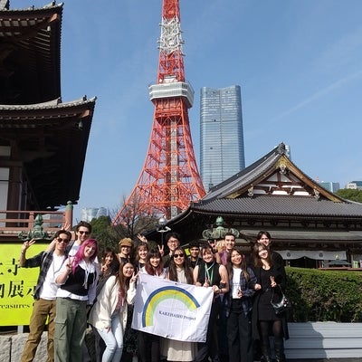 Group shot of participating students. They are holding the Kakehashi sign and you can see the Tokyo tower in the background. 