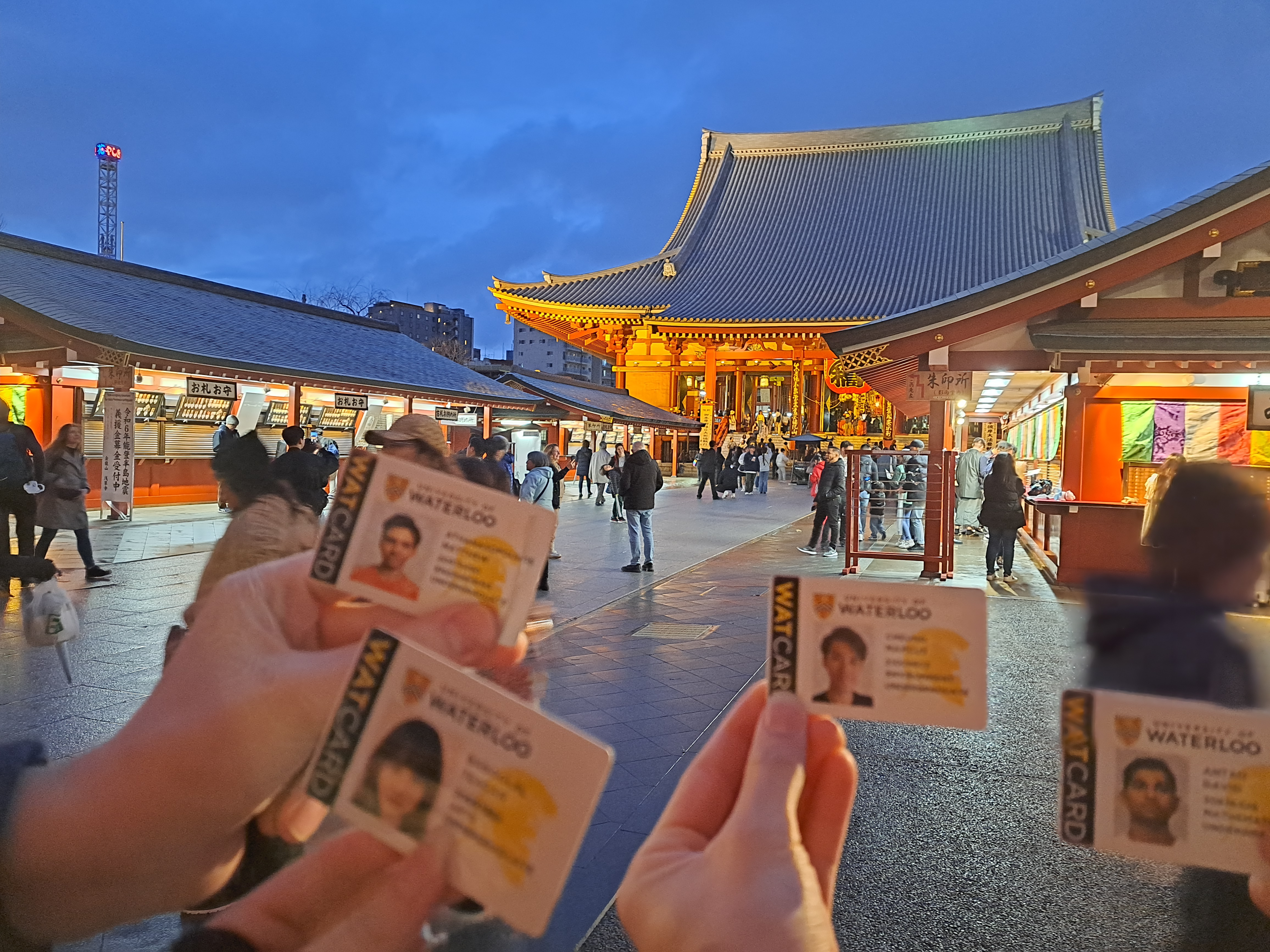 Students hold their watcards up in front of Japanese temple. 