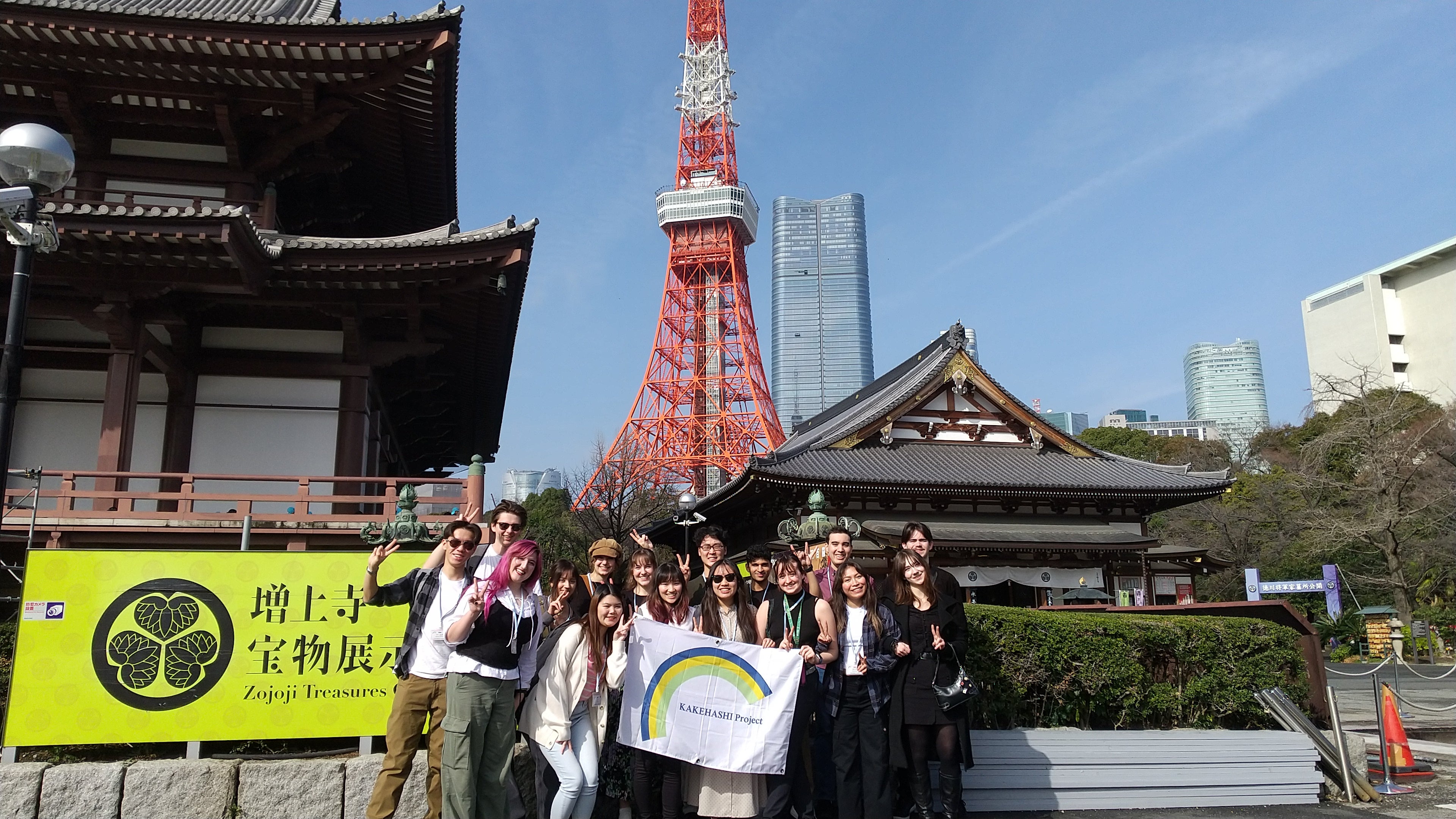 Group shot of participating students. They are holding the Kakehashi sign and you can see the Tokyo tower in the background. 