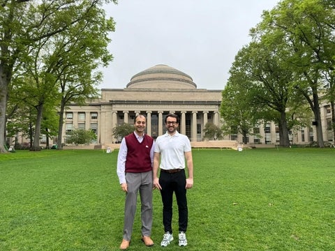 Two men standing infront of the main building at the Massachusetts Institute of Technology