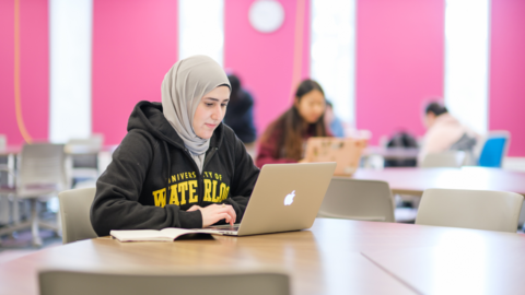 Student sitting at a table working on a laptop