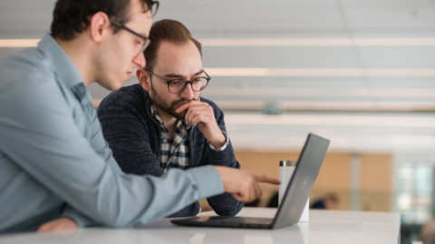 Two students sitting and looking at a laptop