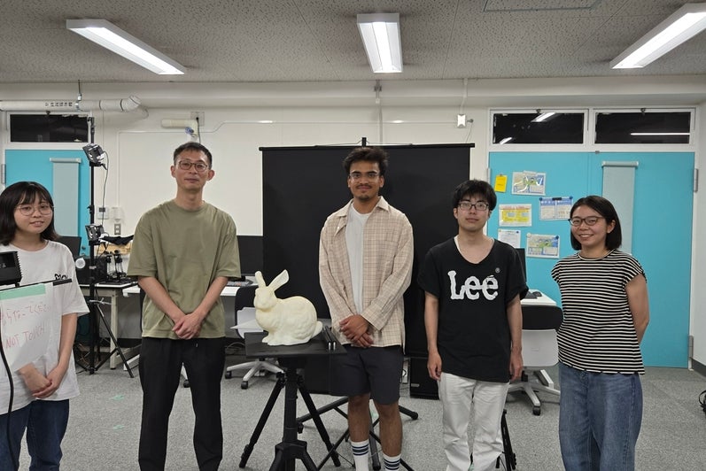 5 people standing in a line behind a ceremic rabbit in a classroom