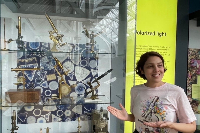 Atiyeh Ahmadi standing beside a display of antique microscopes