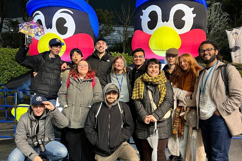 A group of people posing in front of two large inflatable penguins