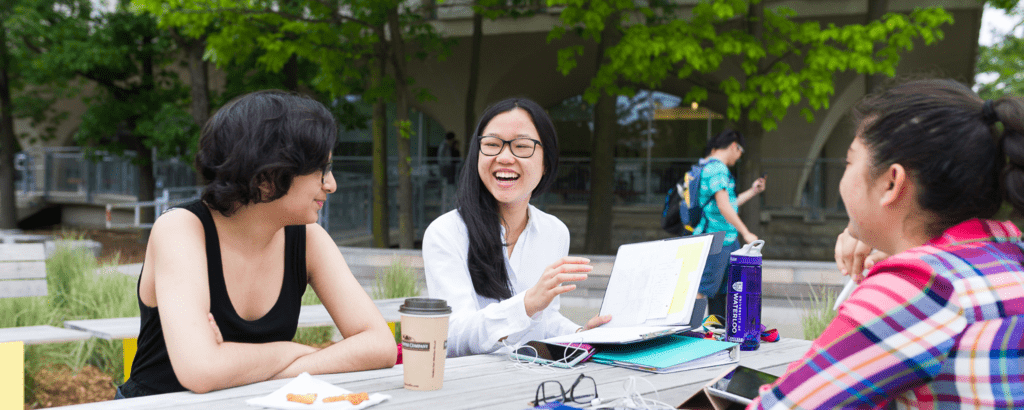 Three students studying at a picnic table.