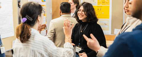 Attendees talking at the poster display at the Cybersecurity Privacy Institute Graduate Student Conference