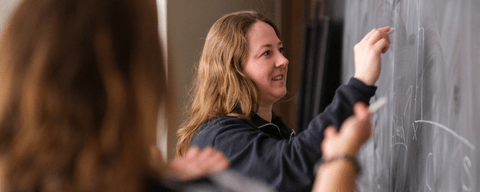 Student writing on chalkboard