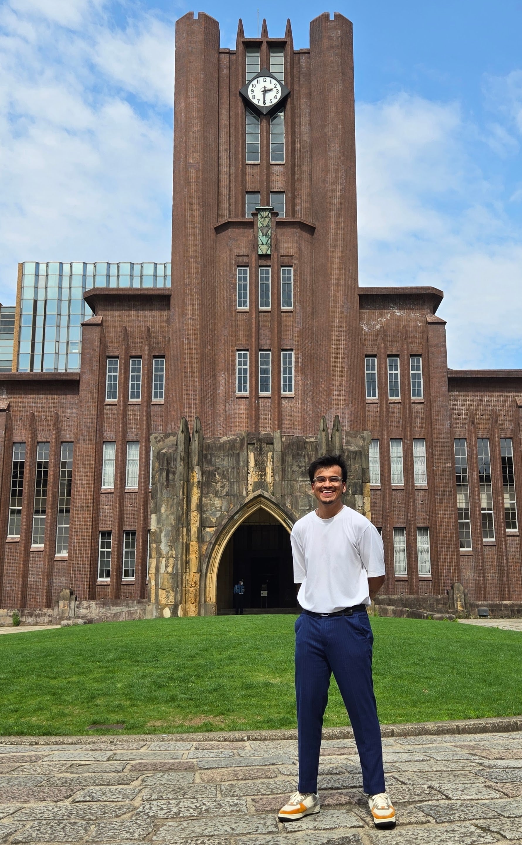 Rishabh Bajaj standing in front of a tall building with a clock at the top.
