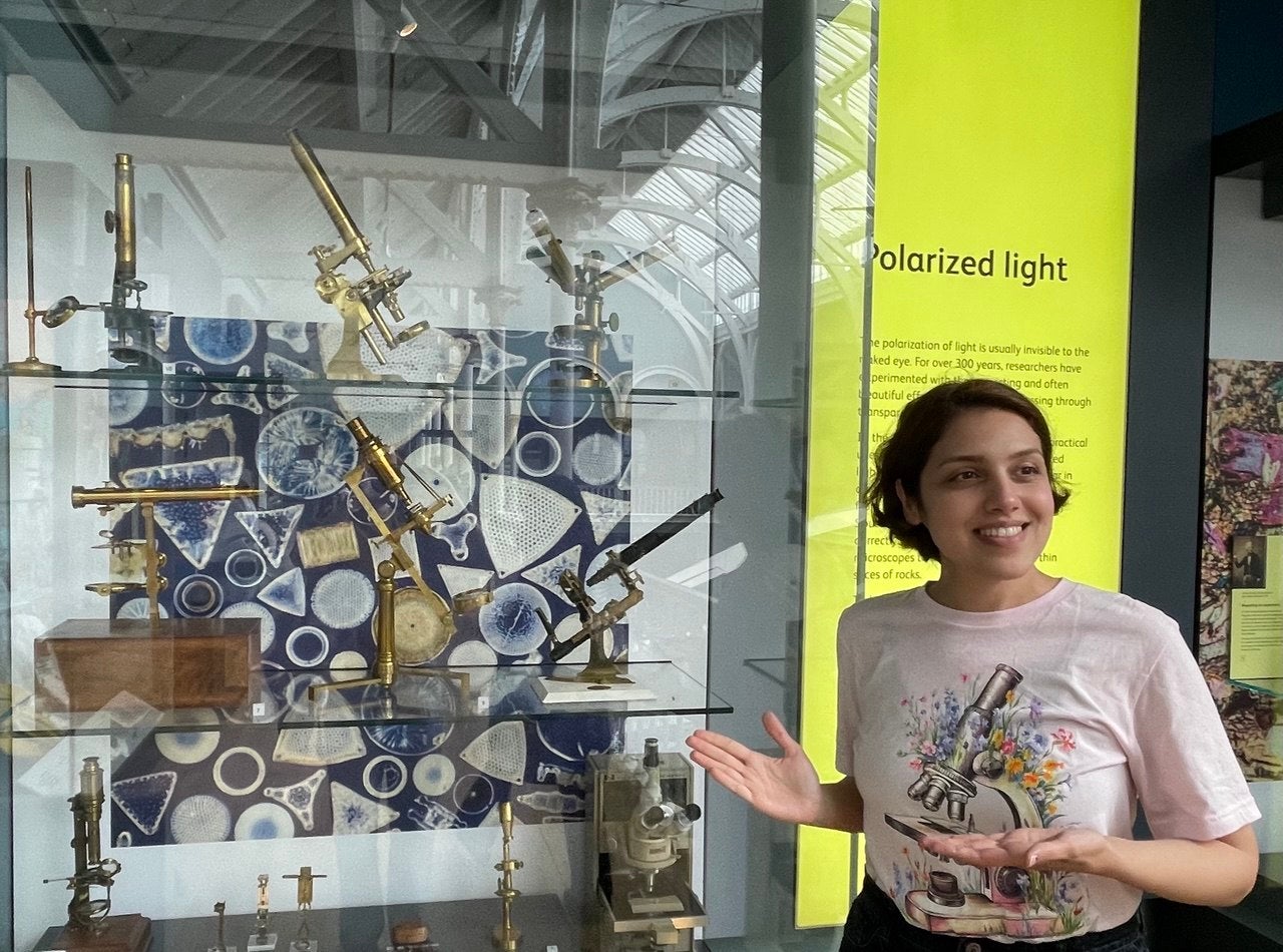 Atiyeh Ahmadi standing beside a display of antique microscopes