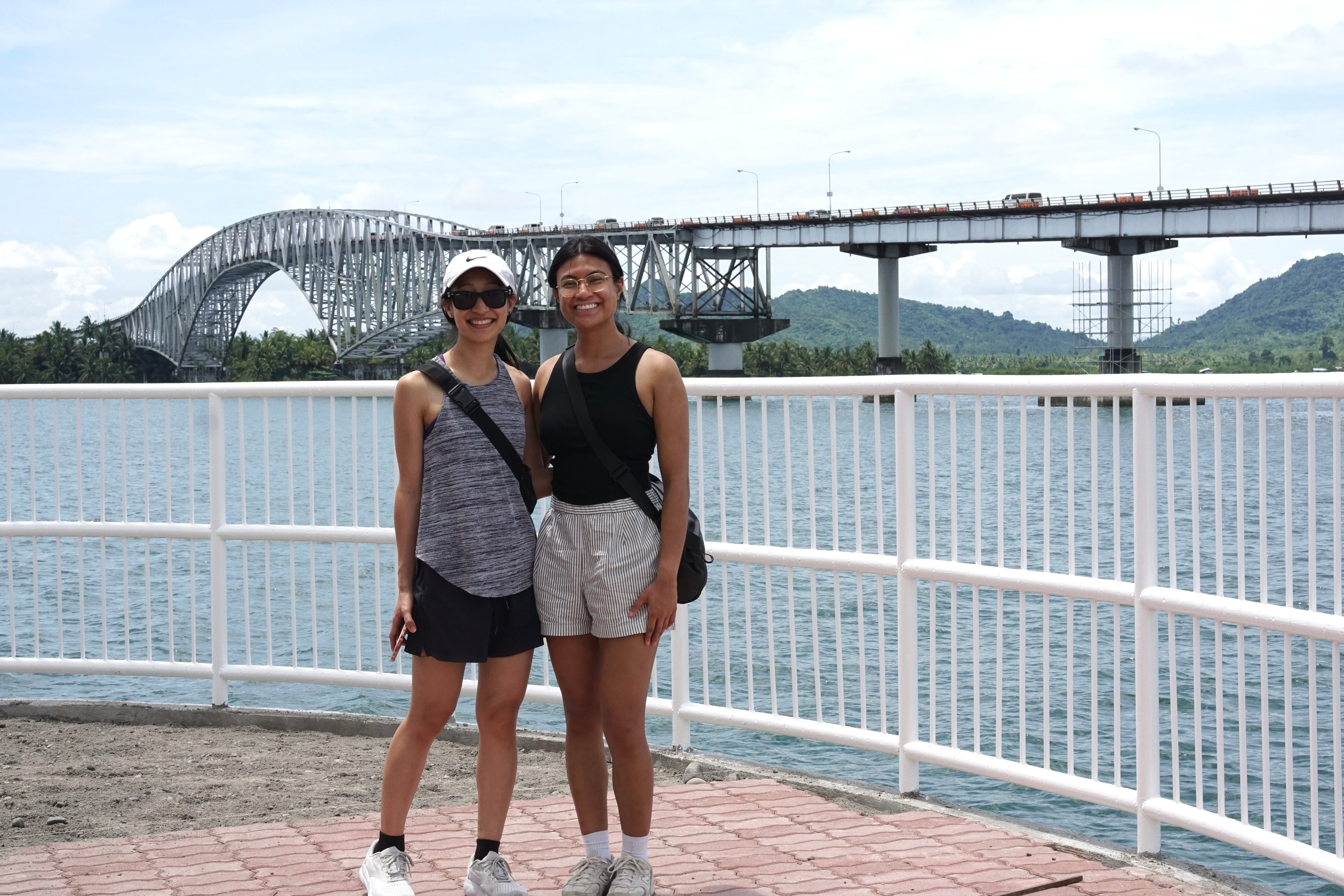 Two people posing and smiling in front of a bridge in the Philippines