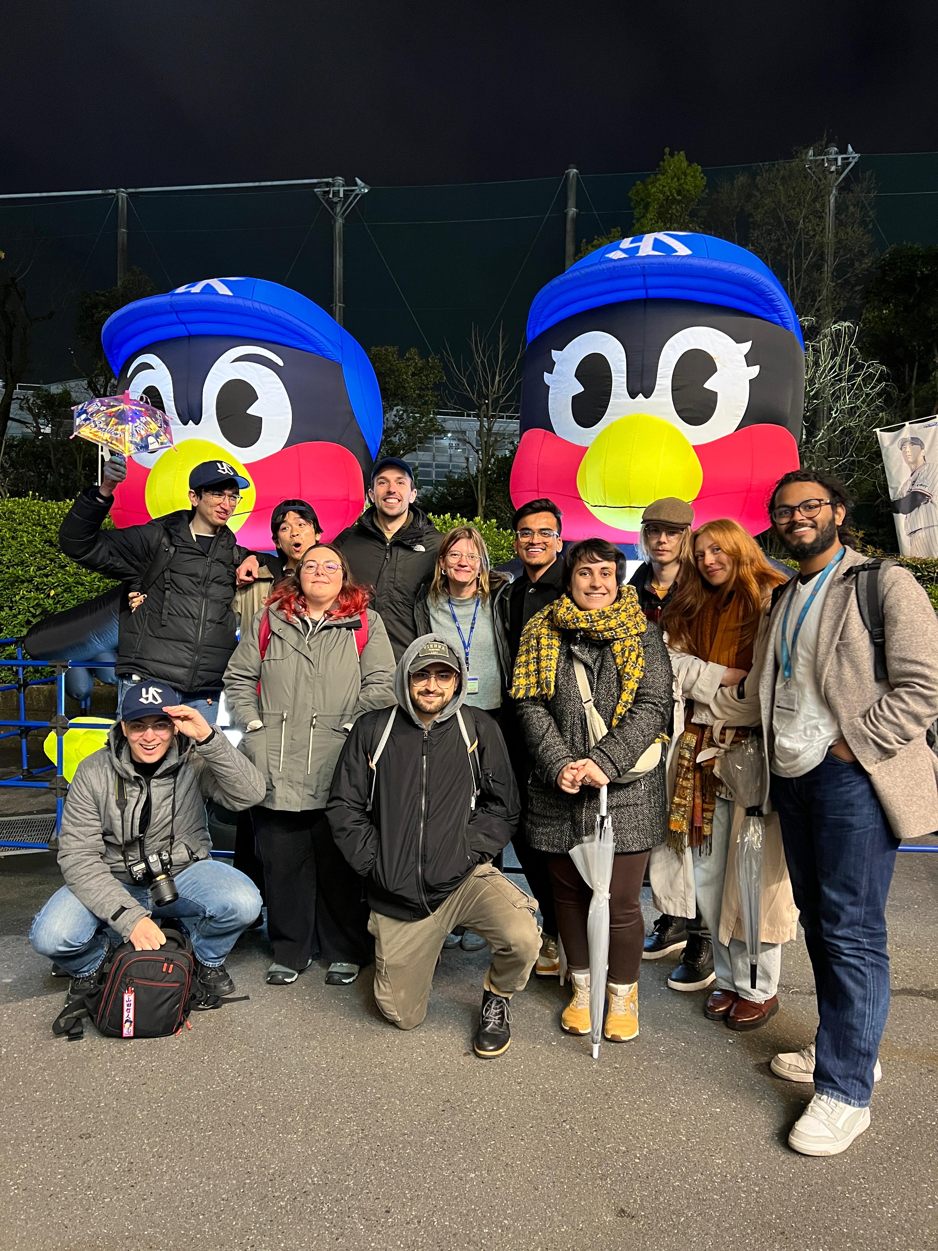 A group of people posing in front of two large inflatable penguins