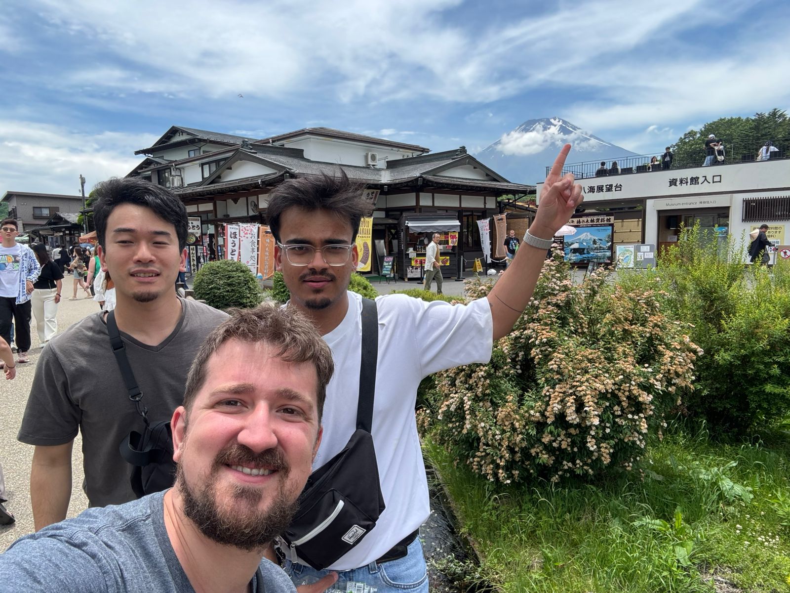 A selfie of 3 people with a building and Mount Fuji in the background