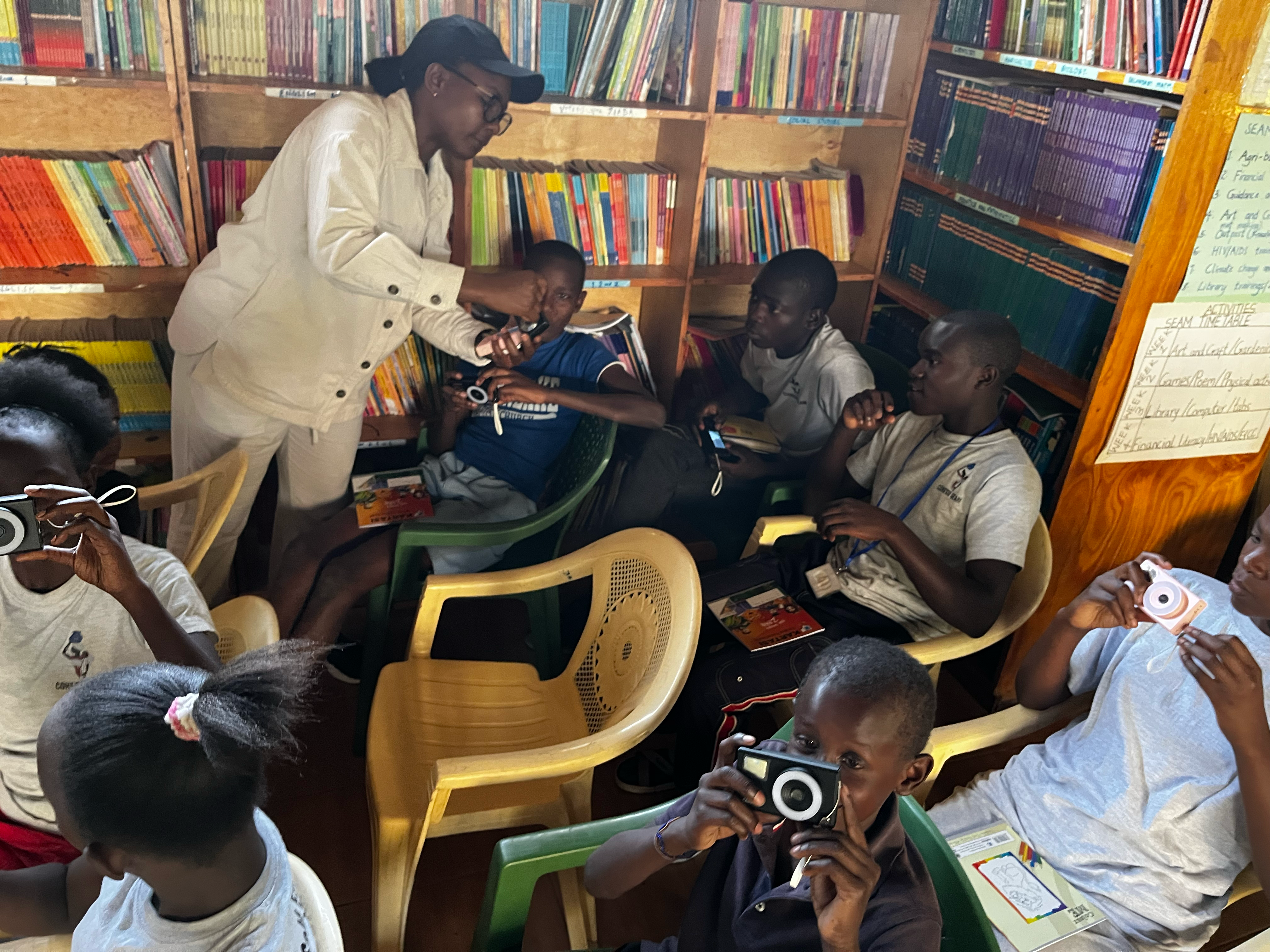 A teacher showing a group of students how to use a camera while in a library