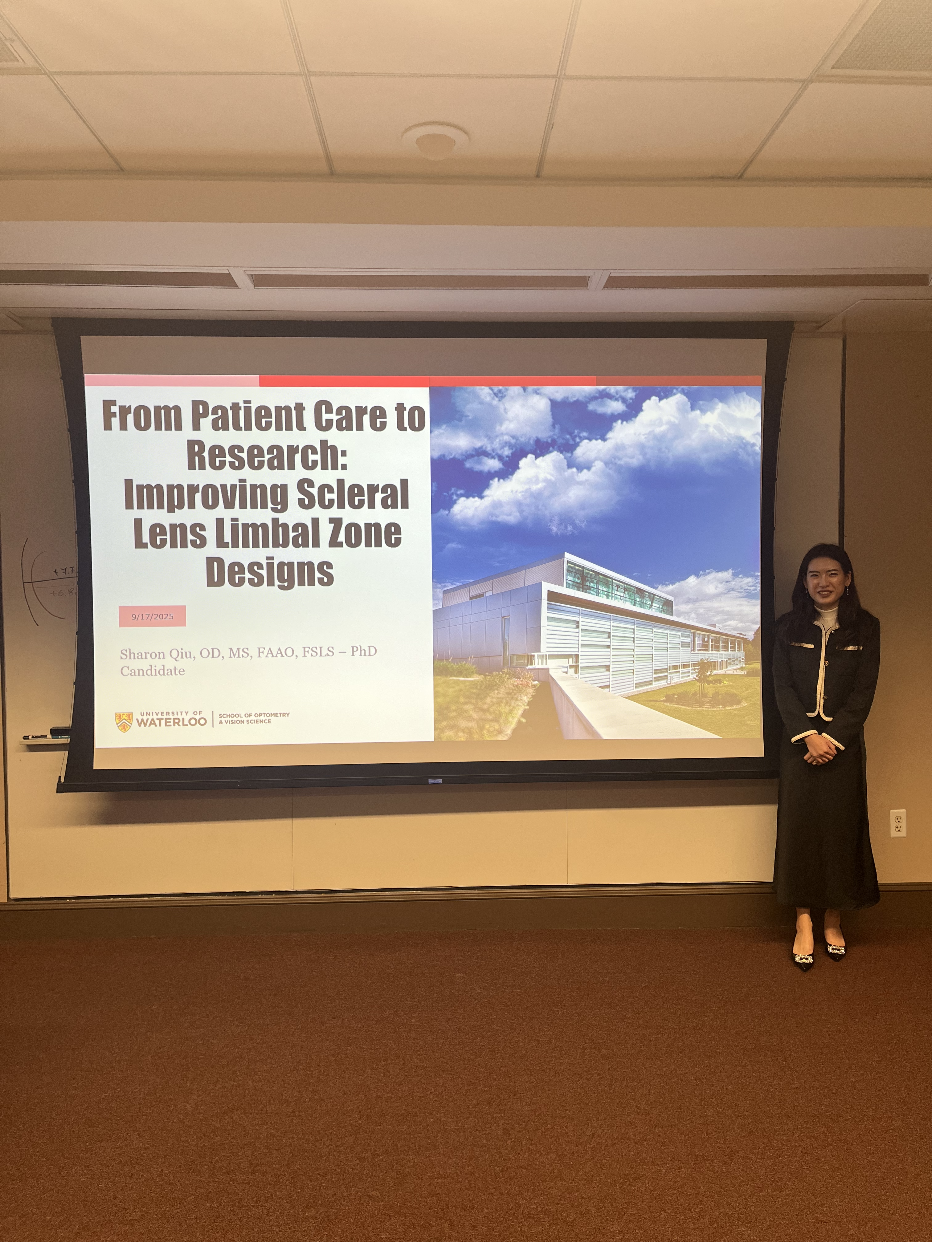 Sharon Qiu standing in front of a presentation screen that reads: "From Patient Care to Research: Improving Scleral Lens Limbal Zone Designs; Sharon Qiu, OD, MS, FAAO, FSLS - PhD Candidate"