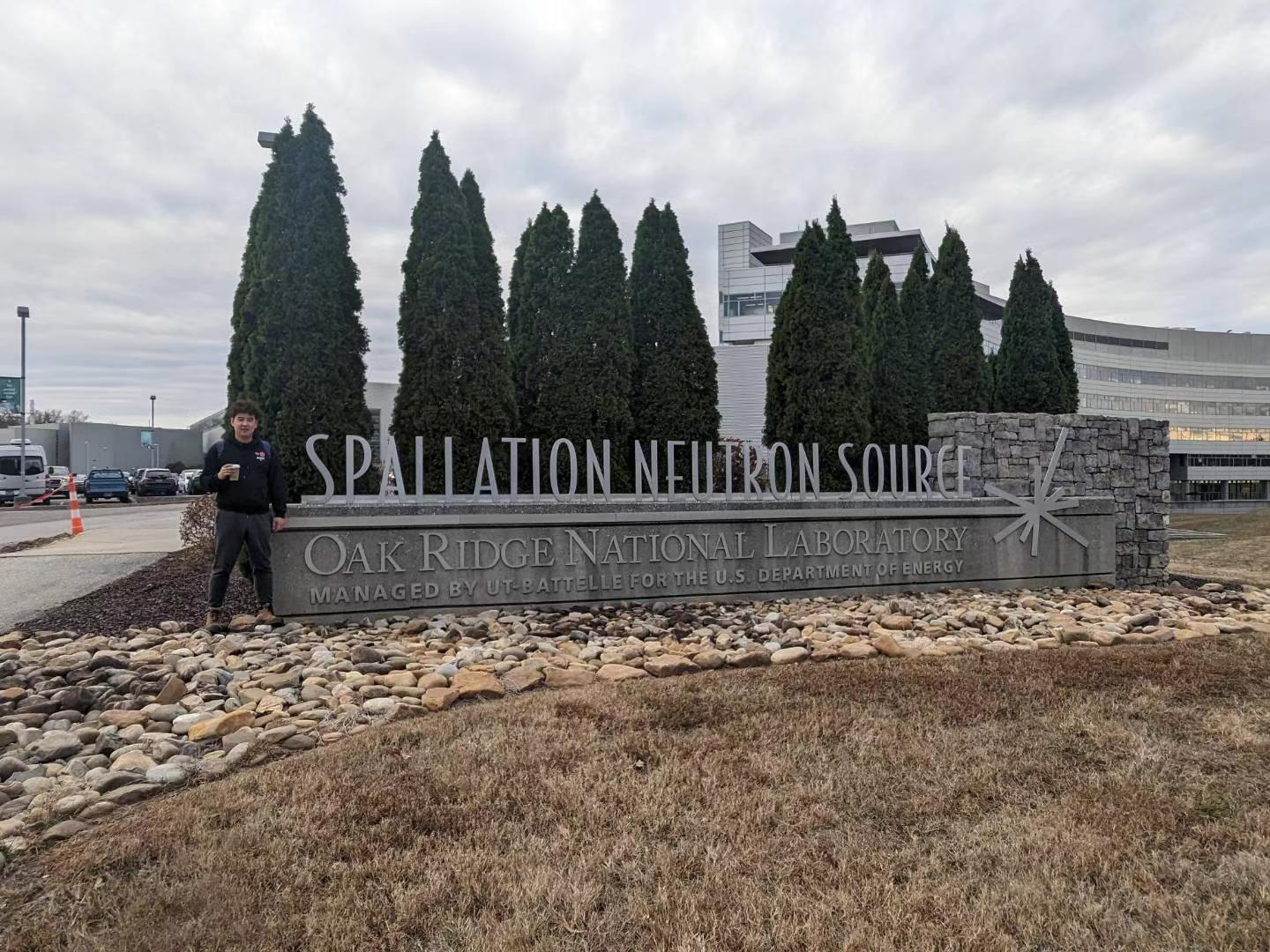 Lanting Qian standing at the sign in front of Oakridge National Lab