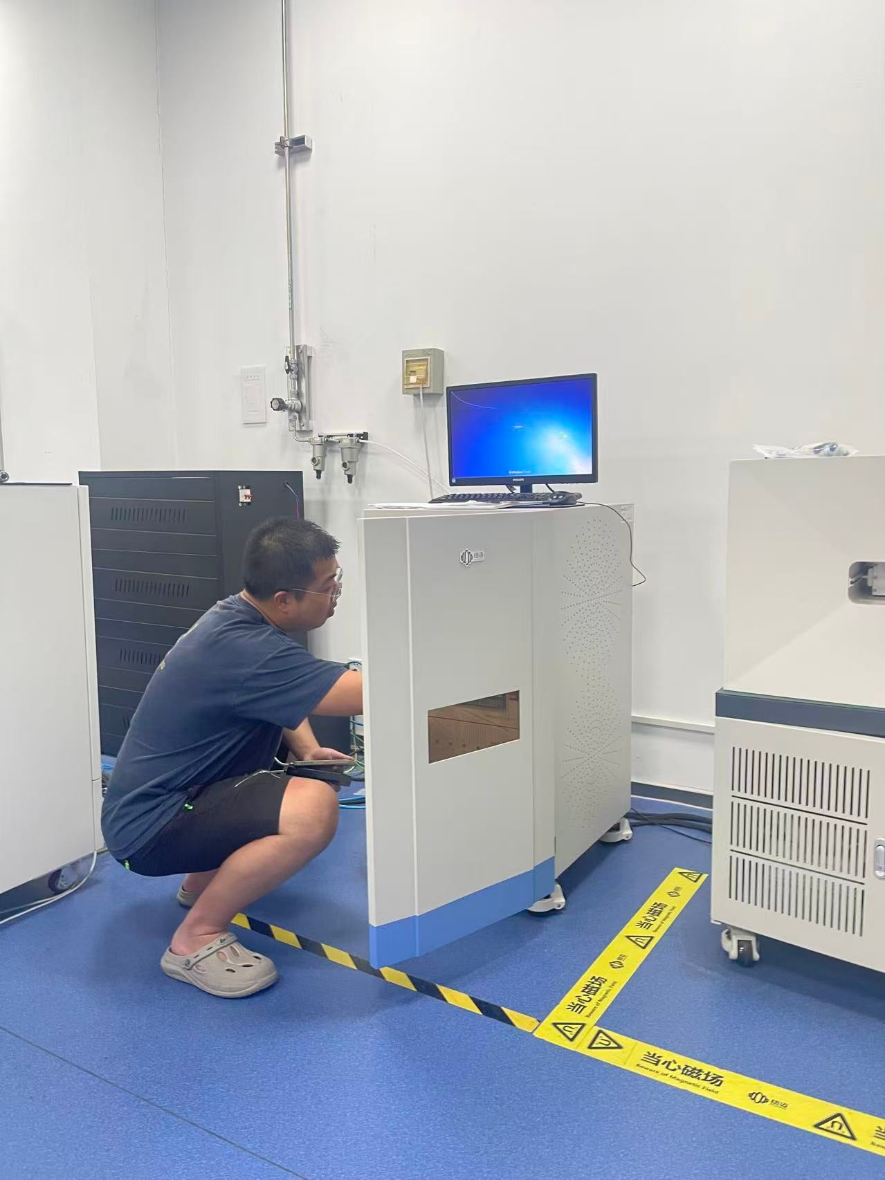 A person reaching inside a cabinet with a compuer sitting on top of it. 