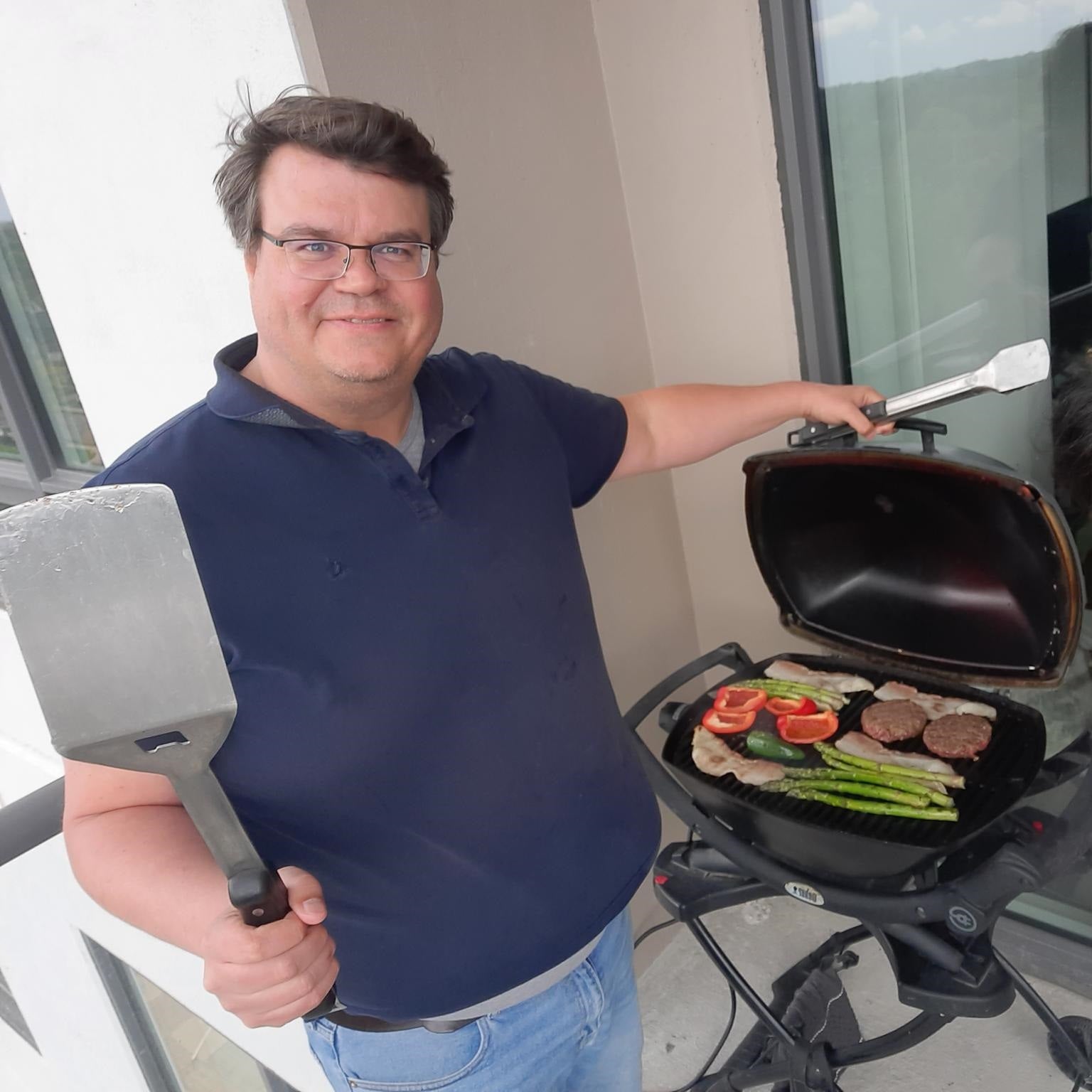 florian kerschbaum holding a spatula while standing in front of a barbecue