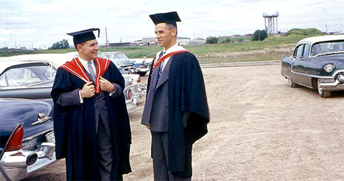 Ted Batke and Arthur Cowan in their academic regalia with the Lester Street Water Tower in the background.