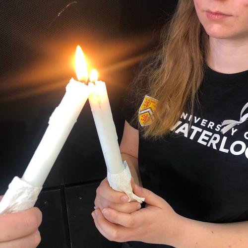 A young woman lights a candle from another candle's flame at the December 6 vigil.