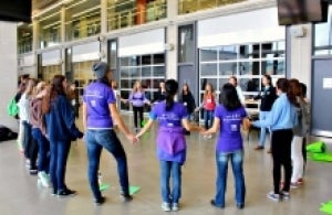 Girls hold hands in a circle at the Sedra Student Design Centre.