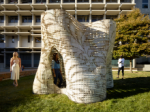 A 3D architectural design wtih people standing next to it.