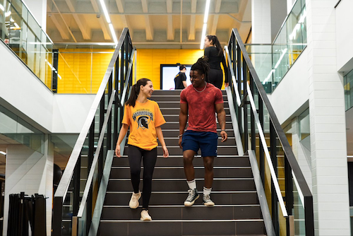 Two Waterloo students walk down a flight of stairs.