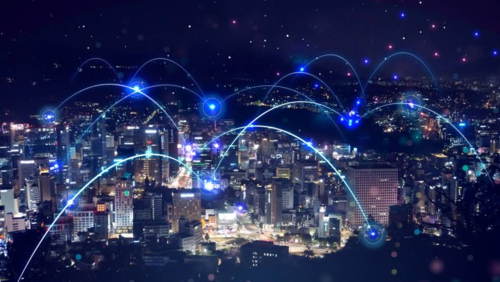 A city's skyline with its buildings connected by arcs of fiber optic lines.
