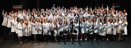 The School of Pharmacy's Class of 2021 poses together with their new white coats.