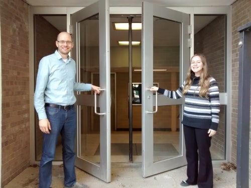 Biology professor Josh Neufeld and graduate student Ashley Ross hold open a set of doors.