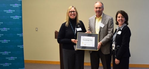 Representatives from Grand River Hospital and the School of Pharmacy pose with a &quot;teaching site&quot; plaque.