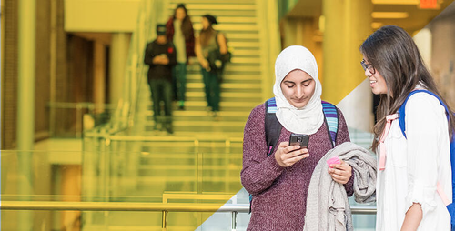 Two women look at a smartphone.