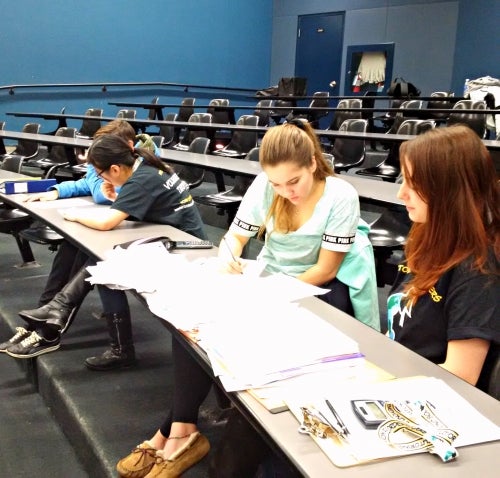 Students and their tutors work in a lecture hall.