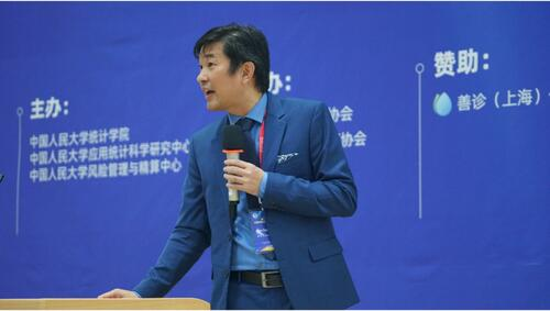 Professor Ken Seng Tan speaks in front of a blue screen.