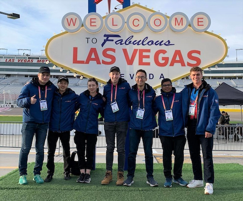 Waterloo team members stand in front of a gaudy Las Vegas speedway sign.