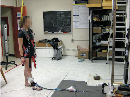 A research study participant prepares to step on tiles while wearing flip flops in a lab.