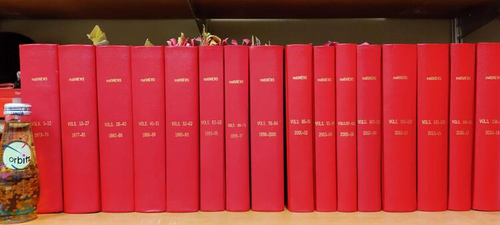 Hardbound copies of mathNEWS in red, flanked by a vintage Orbitz soft drink bottle.