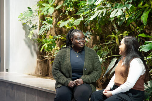 Celine Isimbi speaks with a student next to the Environment Living Wall.