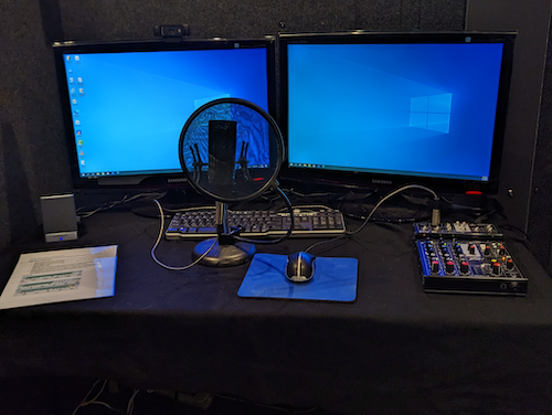 The soundproofed studio setup with a microphone and dual monitor setup.