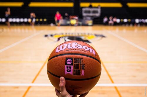A close-up of a basketball with &quot;shoot for the cure&quot; embossed on it.
