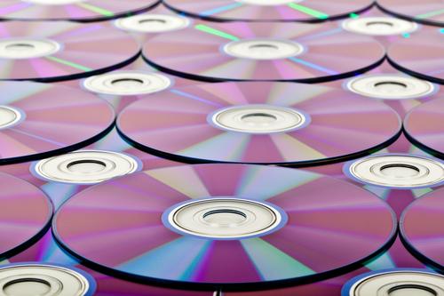 Compact discs layered atop one another, their mirrored surfaces shining.