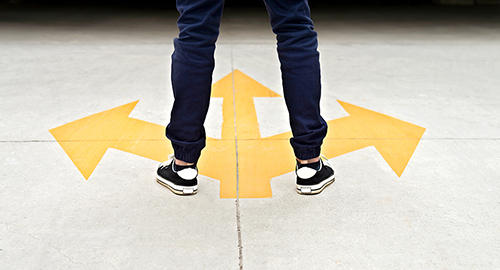 A person's feet and legs stand before a decal with arrows pointing in three directions.
